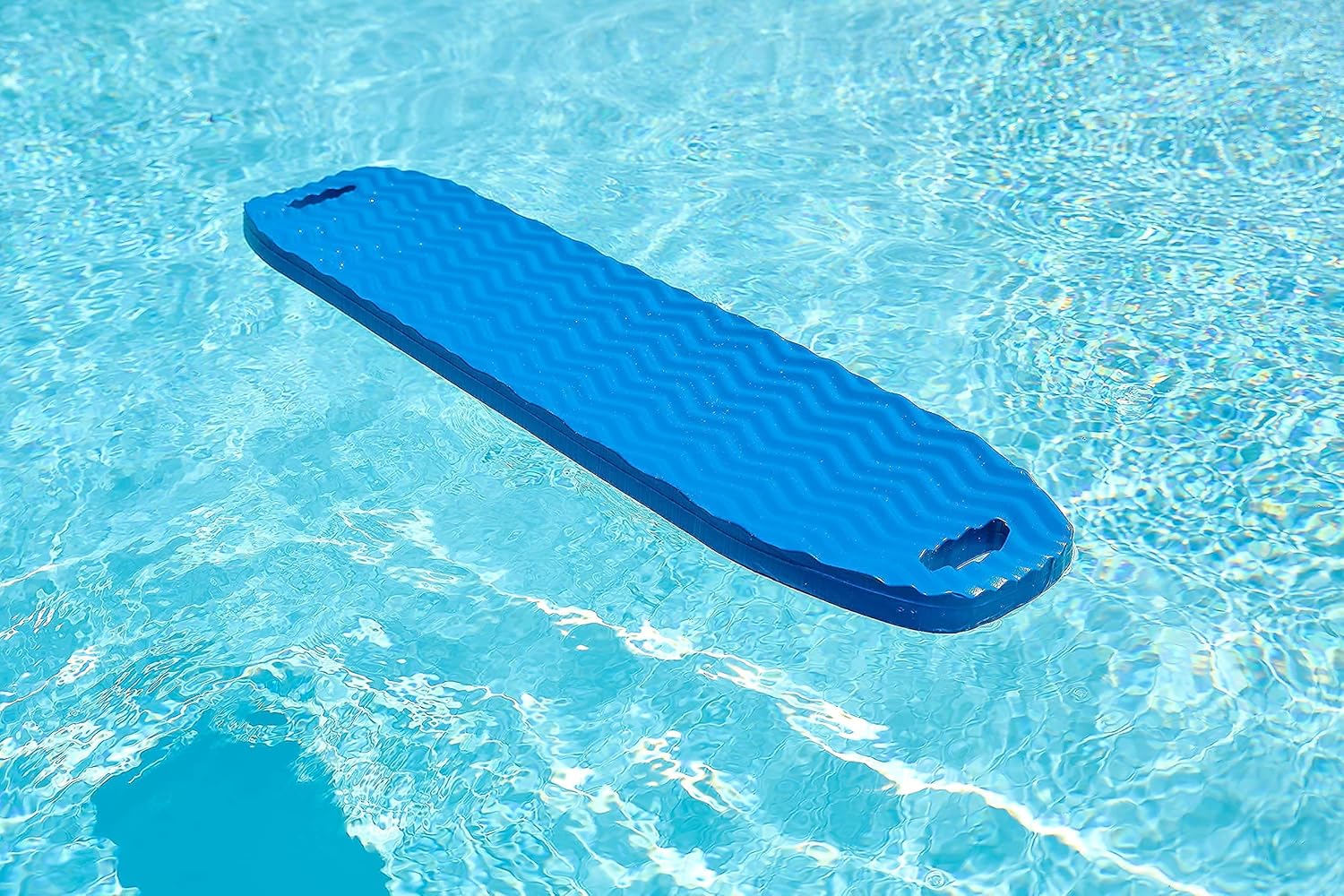 Blue CocoCabana saddle float floating alone in a pool, showing textured surface and handle slots.